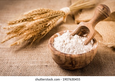 Flour in wooden bowl with grain on burlap background - Shutterstock ID 1907630455