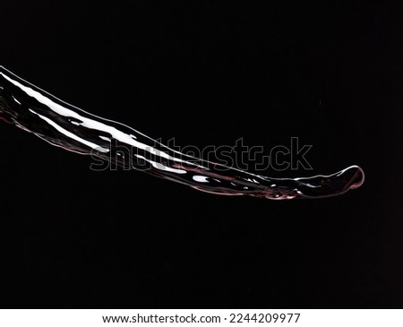 Flow of Crude Oil gasoline pour down over dark background isolated. Black water liquid fall down line. Black Ink, Coffee drink pour splash drop as gold crude oil or sticky water 