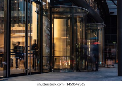  The Flow Of People Passing Through The Revolving Door Of The Modern Office Building At The End Of The Working Day