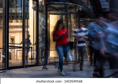  The Flow Of People Passing Through The Revolving Door Of The Modern Office Building At The End Of The Working Day