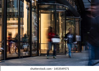  The Flow Of People Passing Through The Revolving Door Of The Modern Office Building At The End Of The Working Day