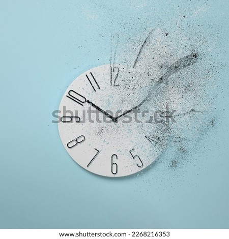 Flow of time. Analog clock dissolving on light blue background