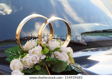 A flower arrangement with big golden rings for a wedding on a black car