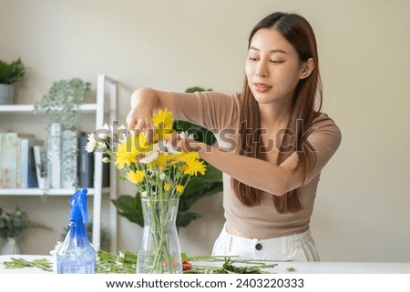 Flower arrangement, happy beautiful asian young woman florist hand making flower in vase, creating bouquet on the table, arranging indoors decor in living room, handmade house interior or decoration.