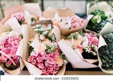 A lot of flower bouquets at the florist shop on the table made of hydrangea, roses, peonies, statice, eustoma in pink and sea green colors - Powered by Shutterstock