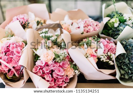 A lot of flower bouquets at the florist shop on the table made of hydrangea, roses, peonies, statice, eustoma in pink and sea green colors