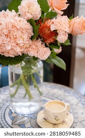 Flower composition. Interior decoration. Ceramic cup with coffee drink near pink hydrangea fresh bouquet in glass vase.