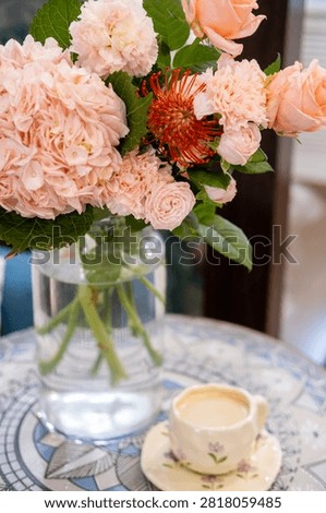 Flower composition. Interior decoration. Ceramic cup with coffee drink near pink hydrangea fresh bouquet in glass vase.