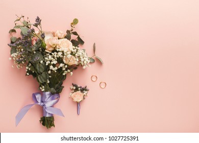 Flower Composition, Wedding Bouquet With Ribbon, Boutonniere And Two Golden Rings, Lying On Pink Table. Wedding Decor, Artwork, Florist, Flat Lay, Top View