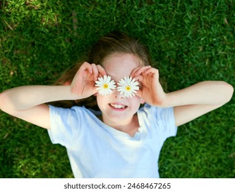 Flower, eyes and girl child in grass field with top view fun, adventure and playing on explore, journey or countryside travel. Daisy, face and happy kid in a garden with creative petal expression - Powered by Shutterstock