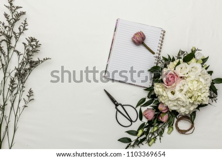 Flower flat lay with notebook and sissors