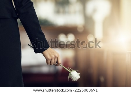 Flower, funeral and hand holding rose in mourning at death ceremony with grief for loss burial. Floral, church or cemetary with person holding plant for sad bereavement or cemetary event in a chapel