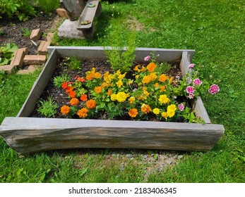 A flower garden box with flowers in full bloom. The impatiens are a mix of gold, pink, and white.