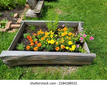 A flower garden box with flowers in full bloom. The impatiens are a mix of gold, pink, and white.
