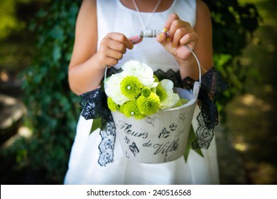 Flower Girl At A Wedding Holding A Basket Of Flowers.