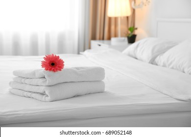 Flower on stack of towels in light hotel room
