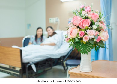 Flower For Patient, Selective Focus On Flower With Patient And Her Visitor Blurred At The Back