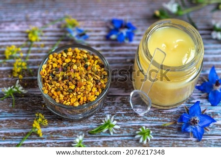 Flower pollen and royal jelly pot in close-up surrounded by flowers