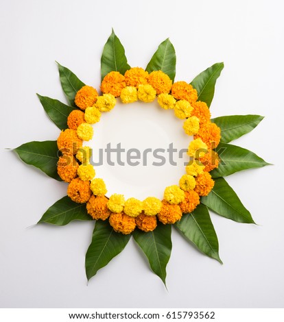 flower rangoli made using marigold or zendu flowers and mango leaves over white background with copy space in the middle, selective focus
