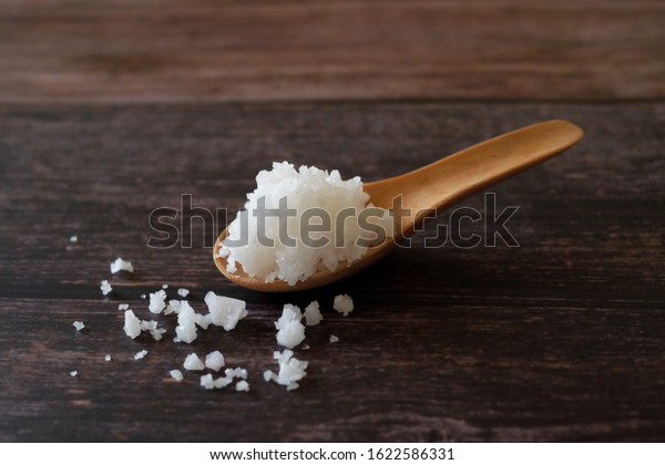 flower of salt, is a salt that forms as a thin, delicate crust on the surface of seawater din the wooden spoon isolated on wooden background. Called Fleur de sel in French.