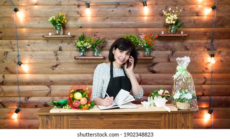 Flower Shop Assistant Talking On The Phone With A Customer.