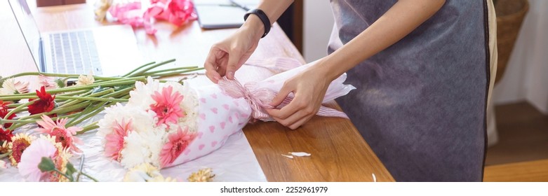 Flower shop concept, Female florist creating colorful flowers bouquet with paper and ribbon bow. - Powered by Shutterstock