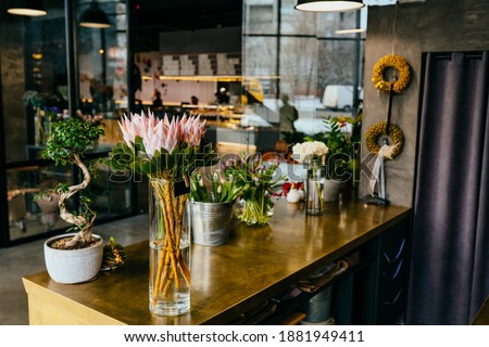 Flower shop loft interior and florist workplace. Different amazing flowers in vases on brass counter in flower shop. Nobody.