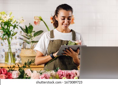 Flower shop owner holding a flower and digital tablet in hands - Powered by Shutterstock