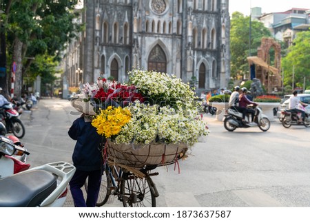 Flower vendor on Hanoi street at early morning with St. Joseph Cathedral church on background