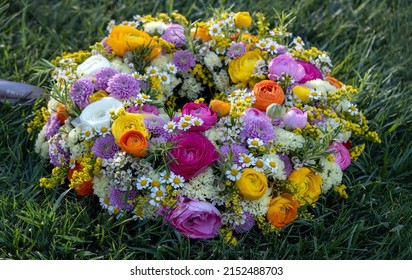 Flower Wreath On Green Grass. Fresh Wild Flowers And Herbs On Garden Lawn, Close Up View. Spring Day. Women Or Mothers Day Celebration