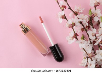 Flowering branch. Spring flowers and lipgloss on a bright pink background. top view.