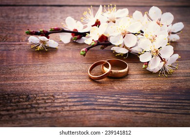 Flowering branch with white delicate flowers on wooden surface. Declaration of love, spring. Wedding card, Valentine's Day greeting. Wedding rings. Wedding bouquet, background.