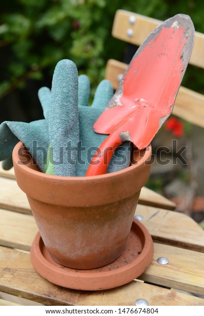 Flowerpot with garden\
gloves and a dibble