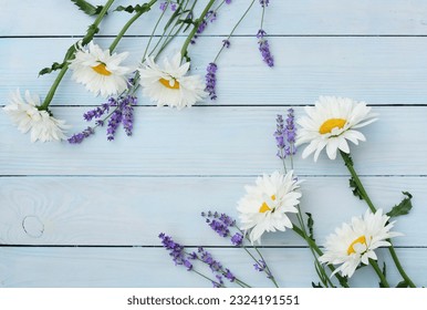 Flowers background with copy space top view. Chamomile daisy and lavender flowers frame template on blue wooden backdrop. Floral card - Powered by Shutterstock