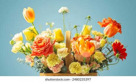 Flowers in basket, closeup, orange and yellow roses, tulip and carnation on blue background