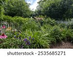 Flowers blooming in the garden with a white pickett fence