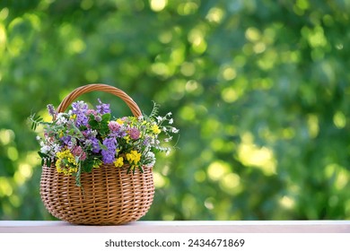 flowers bouquet in wicker basket on table in garden, abstract natural green background. spring, summer season. rustic still life with meadow flowers. template for design. copy space - Powered by Shutterstock