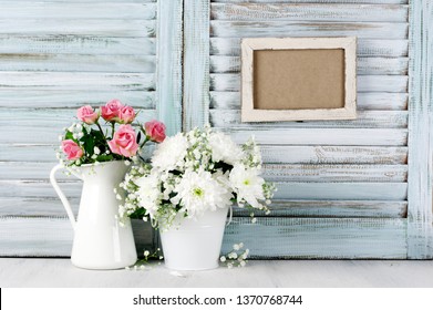 Flowers Bouquets On Wood Table Against Vintage Wooden Shutters With Empty Photoframe. Shabby Chic Style.