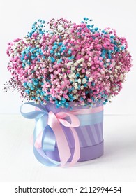 flowers in a box with ribbons in pink and blue on a white wooden table, close-up with a blurred background. a delicate bouquet of multicolored gypsophila as a present for Easter - Shutterstock ID 2112994454