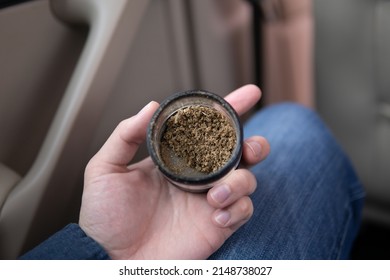 Flowers Of Cannabis. Cannabis In Grinder Joint Vertical Grinder In Hand Weed On A Car Background Close Up Marijuana