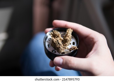 Flowers Of Cannabis. Grinder And Shredded Cannabis In Grinder Joint And A Packet Of Weed On A Car Background Close Up Marijuana Bud