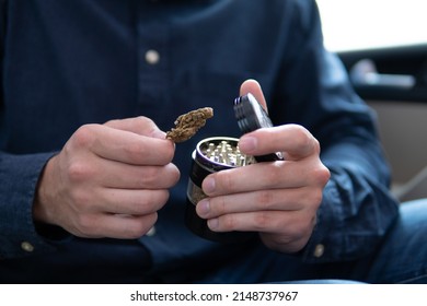 Flowers Of Cannabis. Grinder And Shredded Cannabis Joint Packet Of Weed On A Car Background Close Up Marijuana Joint In Hand Bud