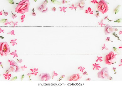 Flowers composition. Frame made of various pink flowers on wooden white background. Flat lay, top view