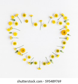 Flowers composition. Heart symbol made of various yellow flowers on white background. Flat lay, top view