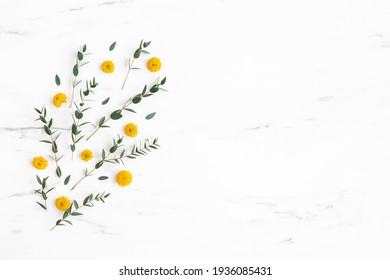 Flowers composition. Yellow flowers and eucalyptus leaves on marble background. Flat lay, top view - Shutterstock ID 1936085431