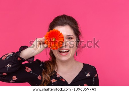 Flowers, emotions and people concept - woman closed her eye with gerbera on pink background