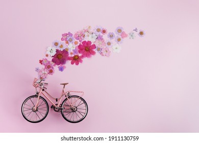 Flowers fly out from pink bicycle bascet on pink background. Romanitic concept for Valentine day, women or mother day.