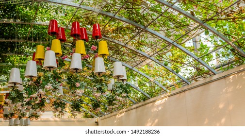 Flowers growing upside down in colorful pots hanging from metal frame roof.
