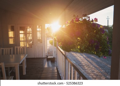 Flowers hang on porch. House and sun shining brightly. It's time to come home. Don't forget your roots. - Powered by Shutterstock