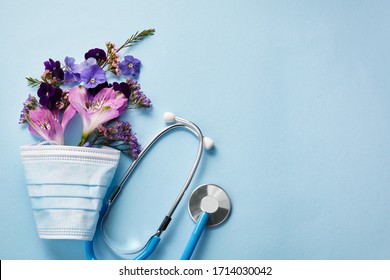 Flowers With Mask And Stethoscope On Blue Background. Happy Nurse Day Concept. Top View